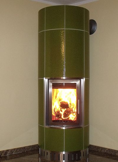 Kaminofen mit glänzend grünen Kacheln und brennendem Feuer