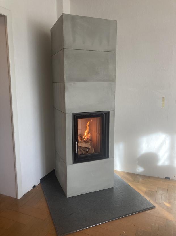 Kaminofen in heller Betonoptik mit Sichtscheibe und Feuer
