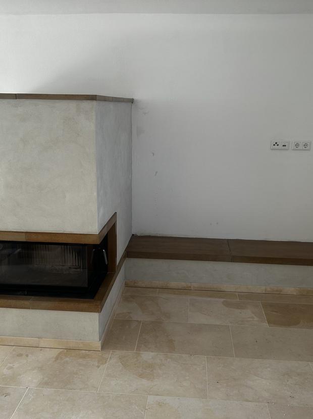 Kamin in Betonoptik mit Sitzbank in einem hellen Raum